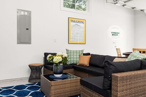 Ein modernes Wohnzimmer mit einem Ecksofa, einem kleinen Beistelltisch, einem Blumenstrauß und einer gerahmten Karte an der Wand.
