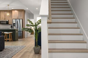 Eine moderne Küche mit Edelstahlgeräten, einer Holztreppe und einem Blumentopf.