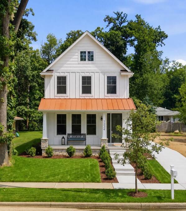 A two-story white house with a red roof, a front porch, and a mailbox. - Across From ND Stadium | Luxury 6B/5BA | Sleeps 14 (South Bend)