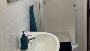Een badkamer met een wit wastafelmeubel, een spiegel, een handdoek en een douche.