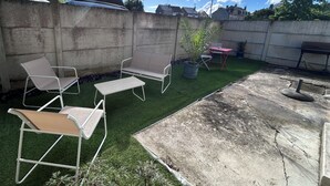 Een terras op het dak met tuinmeubilair, een plant in pot en een barbecue.