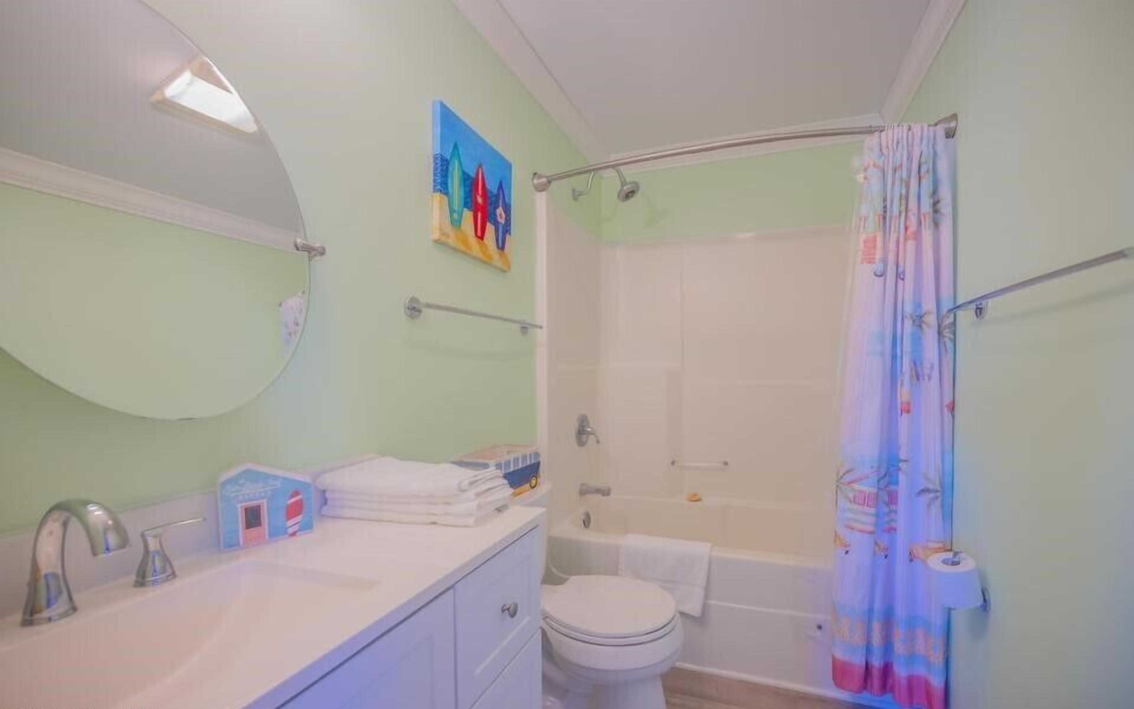A bathroom with a shower, toilet, sink, and a towel rack.