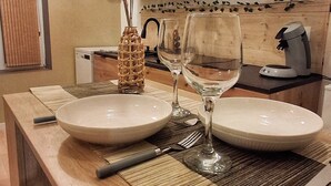 A wooden dining table with two white plates, a glass, and a woven centerpiece. - Deadwood (Berlaimont)