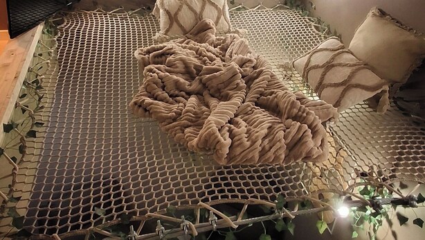 A room with a bed covered in a net, pillows, and a blanket. - Deadwood (Berlaimont)
