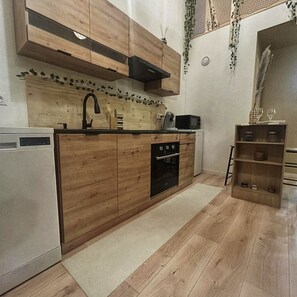 Une cuisine avec des meubles de rangement en bois, un four encastré, un four à micro-ondes et un évier.