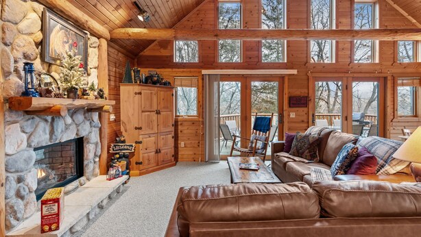 A log cabin interior with a stone fireplace, wooden furniture, and large windows. - Rustic Ridge Cabin 102 - Private Woodland Retreat near Devil's Lake State Park (Merrimac)