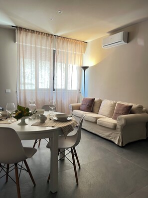 Un coin repas avec une table dressée pour deux personnes, un canapé et une lampe moderne.