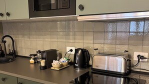 A kitchen with a microwave, toaster, coffee maker, and a sink.