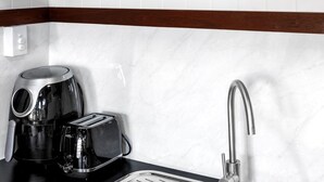A kitchen with a coffee maker, toaster, and a modern faucet. - Modern, exclusive, fully furnished, self-contained 1x1 studio apartment, (Exmouth)