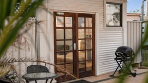 A patio with a grill, a sliding glass door, and a small table. - Modern, exclusive, fully furnished, self-contained 1x1 studio apartment, (Exmouth)