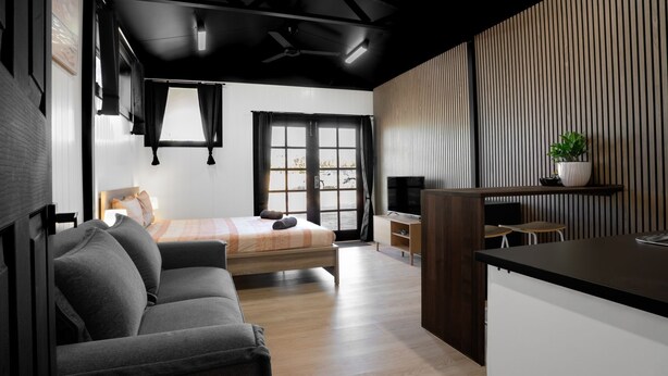 A modern bedroom with a bed, a sofa, a TV, and a kitchen area. - Modern, exclusive, fully furnished, self-contained 1x1 studio apartment, (Exmouth)
