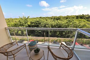 Ein Balkon mit Korbstühlen, einem kleinen Tisch und einem Topfpflanzen.