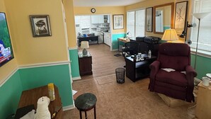 A living room with a sofa, a chair, a small table, and a TV. There is a kitchen in the background. - Studio efficiency in the heart of downtown Saint Augustine (St. Augustine)