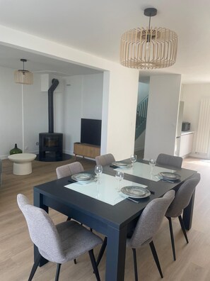 A modern dining area with a black table, grey chairs, and a hanging light fixture. - House with large garden close to beaches. Ideal for families (Saint-Cast-le-Guildo)