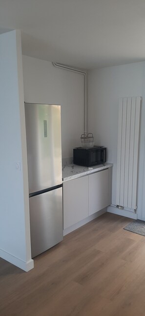 A kitchen with a stainless steel refrigerator, a microwave, and a white cabinet. - House with large garden close to beaches. Ideal for families (Saint-Cast-le-Guildo)