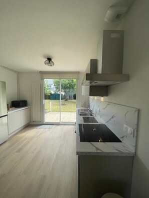 A modern kitchen with a large window, a built-in stove, and a view of the backyard. - House with large garden close to beaches. Ideal for families (Saint-Cast-le-Guildo)