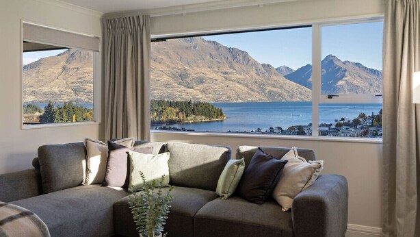 A living room with a large window overlooking a mountainous landscape and a lake. - Spectacular Views, Walk To Town, Freshly Renovated (Queenstown)