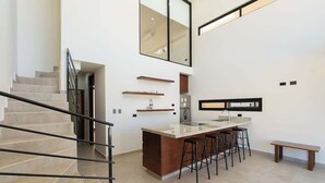 Eine moderne Küche mit einer zentralen Kochinsel, Barhocker und einem eingebauten Backofen.