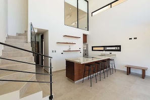 Eine moderne Küche mit einer zentralen Kochinsel, Barhocker und einem eingebauten Backofen.
