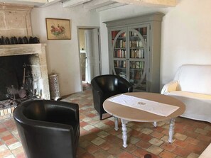 A living room with a fireplace, a bookshelf, a white sofa, and two black chairs. - La Fromagerie - MONDION (MONDION)