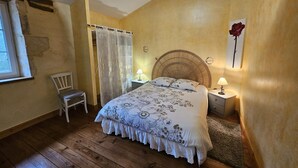 Ein Schlafzimmer mit einem Bett, einem Sessel, einem Fenster und einer Wanddekoration mit Rosen.