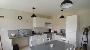 Una cucina moderna con mobili bianchi, un tavolo da pranzo e lampade a sospensione.