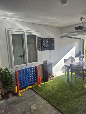 A room with a window, dartboard, and a table with chairs. - Le Gîte de Bré - Near Futuroscope (CHENECHE)