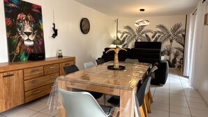 Uma sala de jantar com mesa de madeira, cadeiras, luminária decorativa e um quadro grande na parede.