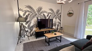 Ein Wohnzimmer mit Fernseher, Lampe, Couchtisch und Sofa.