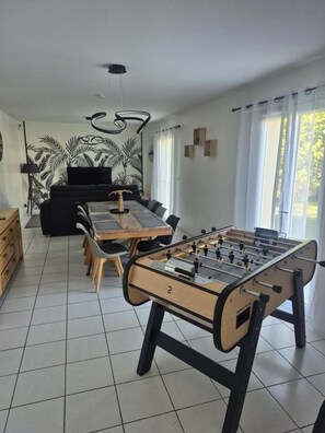 A dining area with a foosball table, a sofa, and a dining table with chairs. - Le Gîte de Bré - Near Futuroscope (CHENECHE)