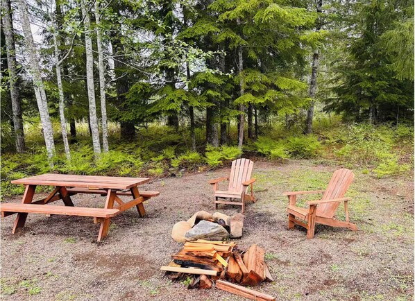 A picnic setup with a table and chairs in a forested area.