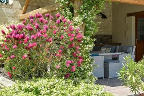 A garden with flowering plants, a wooden pergola, and outdoor furniture. - Domaine du Haut Vernay Scandinave (BOURNAND)
