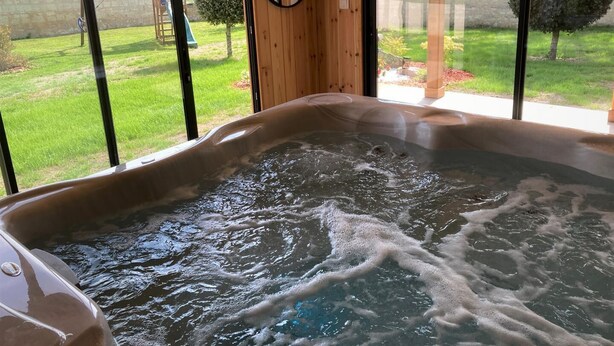 A hot tub with a view of a grassy yard and trees.