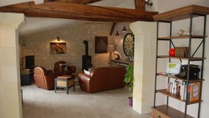 A cozy living room with a fireplace, leather furniture, a bookshelf, and a clock on the wall.