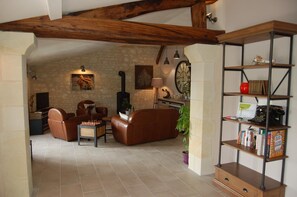Una sala de estar acogedora con chimenea, muebles de cuero, una estantería y un reloj en la pared.