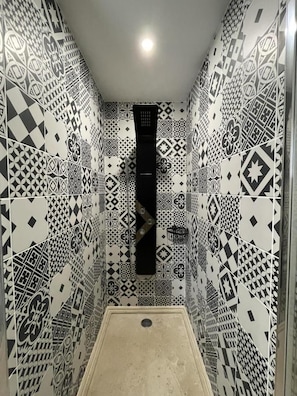 Une salle de bain avec des carreaux décoratifs sur les murs et un espace douche.