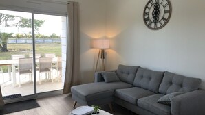 En stue med en grå modulsofa, et hvidt sofabord, en gulvlampe og et vægur.