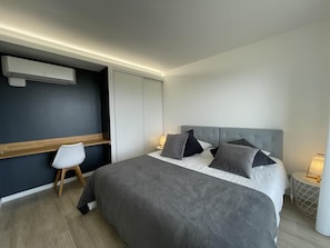 A modern bedroom with a large bed, a bedside table with a lamp, and a built-in air conditioning unit. - Le Monteil - SAINT-JEAN-DE-SAUVES (SAINT-JEAN-DE-SAUVES)