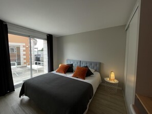 Et hotelværelse med en seng, et natbord med lampe og udsigt ud.