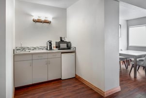Una cocina compacta con microondas, cafetera y refrigerador pequeño.