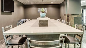 A conference room with a long table, chairs, a vase with flowers, and a television on the wall. - Comfort Inn & Suites Post Falls - Coeur Dalene West (Post Falls)
