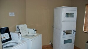 A laundry room with a front-loading washer, a stacked dryer, and a control panel. - Comfort Inn & Suites Post Falls - Coeur Dalene West (Post Falls)