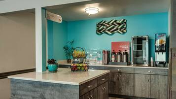 A kitchen area with a central island, a coffee station, and a juice dispenser.