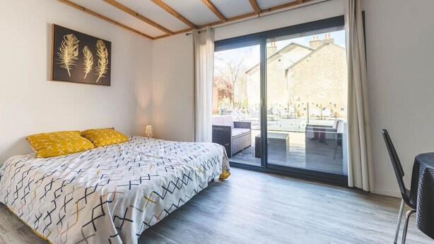 A bedroom with a bed, a large sliding glass door to a balcony, and a framed artwork on the wall. - Le Gite du Marronnier (MONTAMISE)