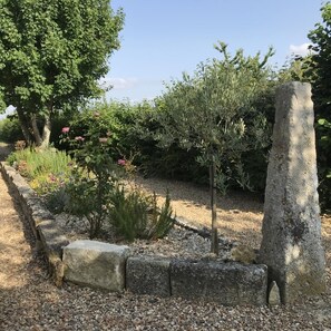 A garden with a stone pathway, a variety of plants, and a large tree. - L'Abri Simonne - LAVOUX (LAVOUX)