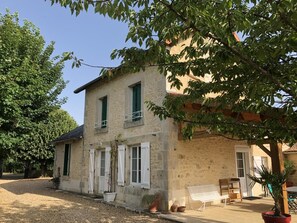 A stone building with white shutters, a balcony, and potted plants. - L'Abri Simonne - LAVOUX (LAVOUX)