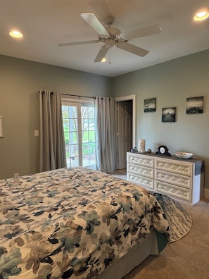Ein Schlafzimmer mit Bett, Deckenventilator, Kommode und Blick durch eine Tür.