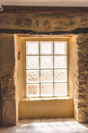 Una habitación con paredes de piedra y un ventanal con divisiones cuadriculadas.