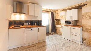 A compact kitchen with white cabinets, a built-in microwave, and a wooden countertop. - Le Gite du Puits - MONTAMISE (MONTAMISE)