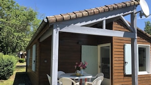A wooden cabin with a covered patio, a dining table with chairs, and a satellite dish. - Chalet N° 5 - SAINT SECONDIN (SAINT SECONDIN)